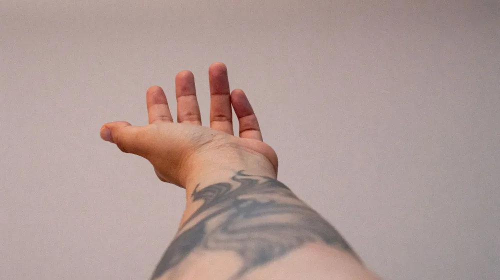 Mano con un tatuaje de tinta minimalista en el antebrazo